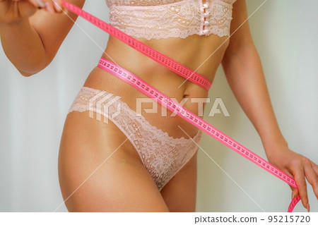 Close up of slim woman measuring her waist's size with tape measure. Isolated on white background. Close up of slim woman measuring her waist's size with tape measure. Isolated on white background. 95215720