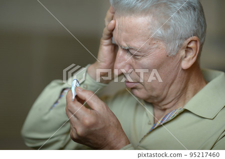 Portrait of an elderly man holding a thermometer. Portrait of an elderly man holding a thermometer. 95217460