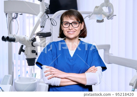 Portrait of smiling mature female dentist looking at camera in office Portrait of smiling mature female dentist looking at camera in office 95218420