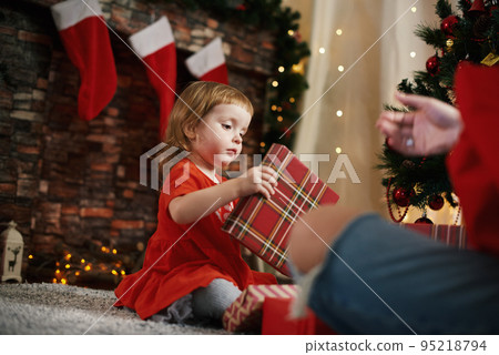 Giving gifts. Little girl with Christmas gifts. Happy family Christmas time by the fireplace 95218794