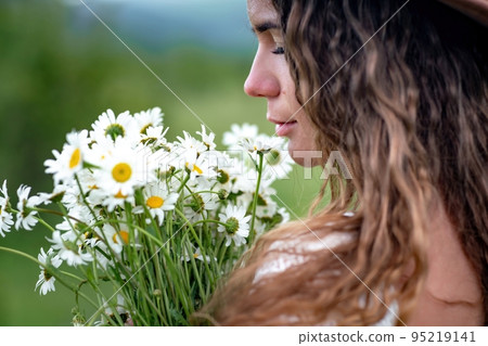 A middle-aged woman holds a large bouquet of daisies in her hands. Wildflowers for congratulations A middle-aged woman holds a large bouquet of daisies in her hands. Wildflowers for congratulations 95219141