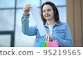 Young woman looks at the prices of goods on a cash receipt after shopping in a mall 95219565
