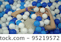 The boy fools around in the pool with colorful plastic balls and throws them 95219572