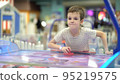 A boy of seven years old enjoys playing air hockey in the playground for entertainment 95219575