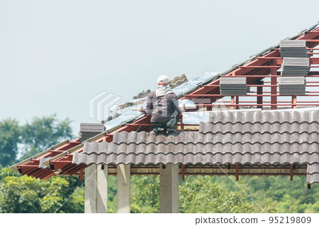 Construction roofer installing roof tiles at house building site Construction roofer installing roof tiles at house building site 95219809