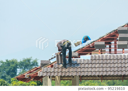 Construction roofer installing roof tiles at house building site 95219810