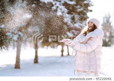 Happy woman in winter style clothes walking in the snowy park. Nature, holidays, travel concept. Happy woman in winter style clothes walking in the snowy park. Nature, holidays, travel concept. 95220048