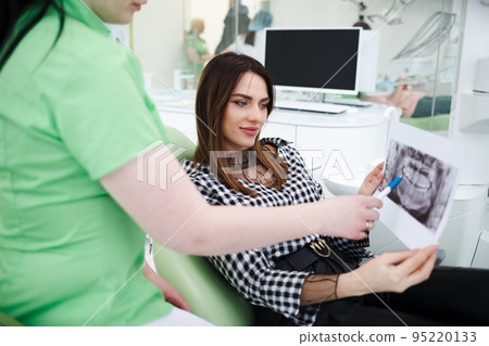 Dentist doctor shows an x-ray of the oral cavity to his patient. 95220133