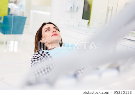 Female patient lies in the dental chair waiting for the treatment process. 95220138