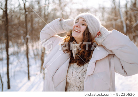 Young woman in winter style clothes walking in the snowy park. Winter fashion, holidays. Young woman in winter style clothes walking in the snowy park. Winter fashion, holidays. 95220620
