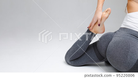 Woman doing yoga and stretching barefoot in studio on gray background 95220806