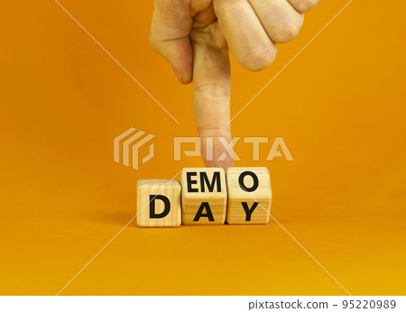 Demo day symbol. Concept words Demo day on wooden cubes. Businessman hand. Beautiful orange table orange background. Business and demo day concept. Copy space. Demo day symbol. Concept words Demo day on wooden cubes. Businessman hand. Beautiful orange table orange background. Business and demo day concept. Copy space. 95220989