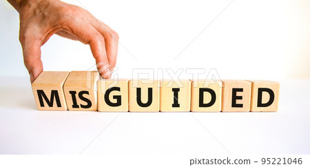 Guided or misguided symbol. Businessman turns wooden cubes and changes the word misguided to guided. Beautiful white table, white background, copy space. Business and guided or misguided concept. Guided or misguided symbol. Businessman turns wooden cubes and changes the word misguided to guided. Beautiful white table, white background, copy space. Business and guided or misguided concept. 95221046