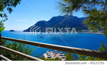 Icmeler Beach view in Marmaris Town. Summer landscape on the Mediterranean coast in Turkey. View of the bay and mountains through pine branches 95221791