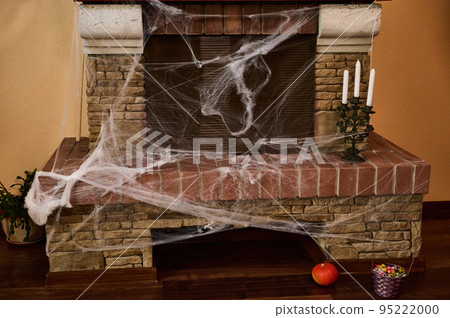 A cobweb-covered stone fireplace with candles on a rusty candlestick. Halloween house decoration. October 31. Home decor. Interior Design. Gothic holiday A cobweb-covered stone fireplace with candles on a rusty candlestick. Halloween house decoration. October 31. Home decor. Interior Design. Gothic holiday 95222000