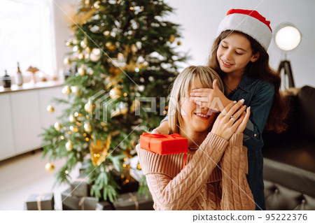 Happy mom and her cute daughter girl exchanging gifts. Merry Christmas and Happy Holidays. 95222376