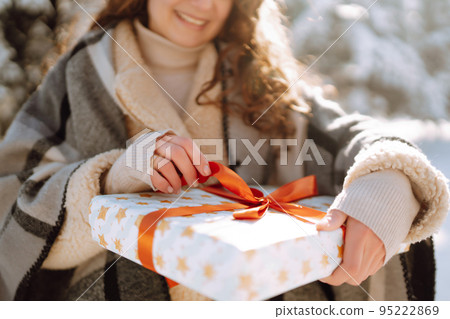 Pretty Woman holding a giftbox with red ribbon in the winter park. Happy winter time. New year's. Pretty Woman holding a giftbox with red ribbon in the winter park. Happy winter time. New year's. 95222869