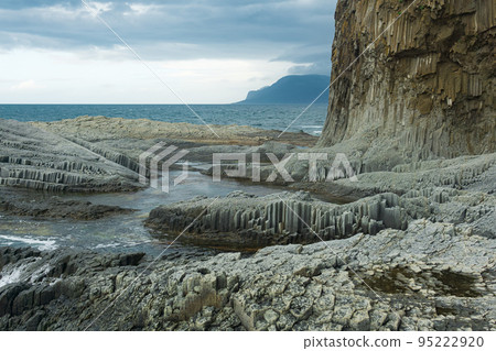 rocky seashore formed by columnar basalt against the backdrop of a stormy sea, coastal landscape of the Kuril Islands rocky seashore formed by columnar basalt against the backdrop of a stormy sea, coastal landscape of the Kuril Islands 95222920