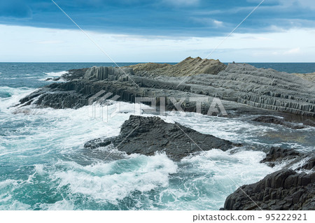rocky seashore formed by columnar basalt against the backdrop of a stormy sea, coastal landscape of the Kuril Islands rocky seashore formed by columnar basalt against the backdrop of a stormy sea, coastal landscape of the Kuril Islands 95222921
