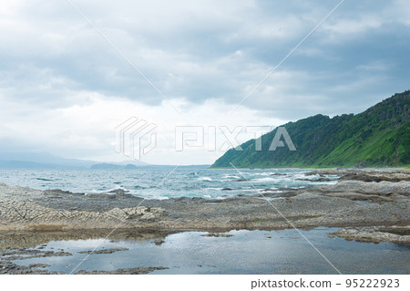 coastal landscape  with beautiful columnar basalt cliff on the wooded coast of Kunashir island 95222923