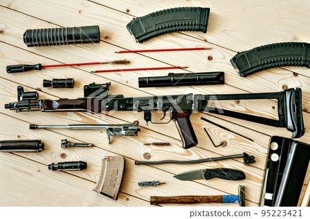 Disassembled rifle with cleaning tools on table of weapons workshop 95223421