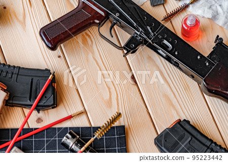 Black disassembled shotgun and cleaning tools on wooden table . Black disassembled shotgun and cleaning tools on wooden table . 95223442