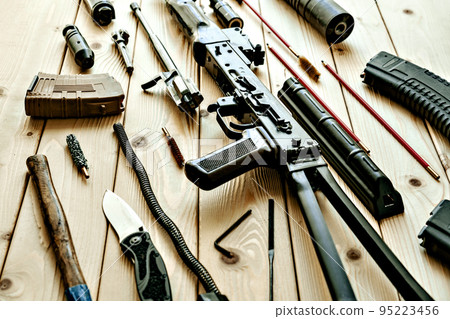 Disassembled rifle with cleaning tools on table of weapons workshop Disassembled rifle with cleaning tools on table of weapons workshop 95223456