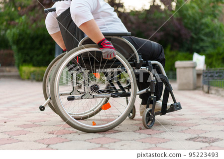 Unrecognizable woman with disability sitting in wheelchair in the street close up Unrecognizable woman with disability sitting in wheelchair in the street close up 95223493