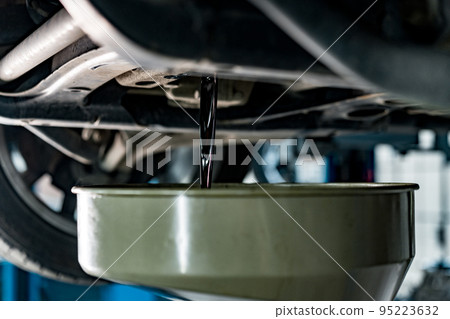 Old dirty oil pouring from the car engine in car service station close up 95223632