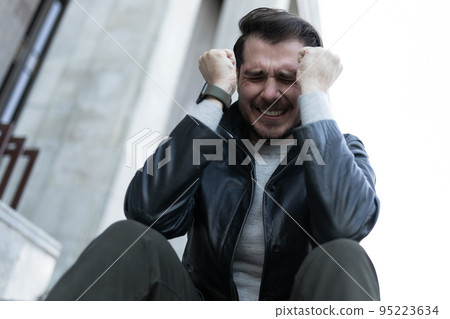 a man at the time of a panic attack sits in the city on the steps a man at the time of a panic attack sits in the city on the steps 95223634