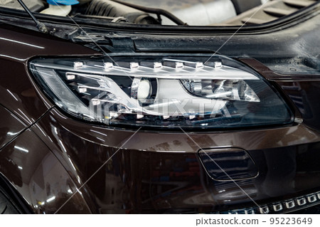 Car headlights and open hood in auto service garage 95223649