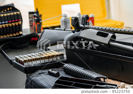 Shotgun rifle with cartridges on table in a weapon workshop Shotgun rifle with cartridges on table in a weapon workshop 95223750