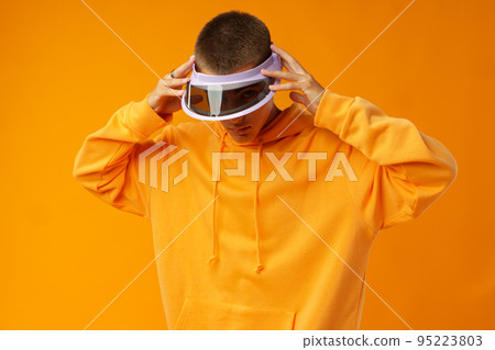 Young urban style man in sweatshirt and visor on yellow studio background 95223803