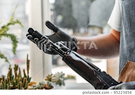 Close up of young man in apron disassembling a gun above the table Close up of young man in apron disassembling a gun above the table 95223856