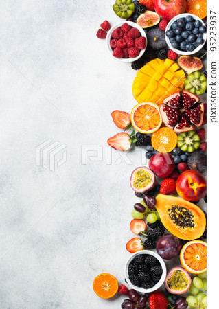 Healthy raw rainbow fruits background, mango papaya strawberries oranges passion fruits berries on oval serving plate on light kitchen top, top view, copy space, selective focus 95223937