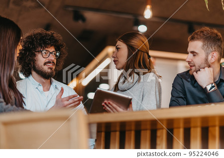 A group of young entrepreneurs on a coffee break discuss the project while using modern editing tablets, a smartphone and a laptop.Business concept 95224046