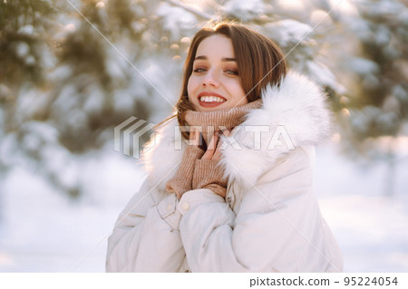 Beautiful woman in winter clothes posing in a snowy park. Young lady walking in a sunny winter day. Beautiful woman in winter clothes posing in a snowy park. Young lady walking in a sunny winter day. 95224054