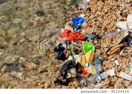 Garbage on a bank of ocean. Pollution of sea, ocean water with waste, plastics garbage. Concept of pollution of ocean, sea and river coastline with plastic trash Garbage on a bank of ocean. Pollution of sea, ocean water with waste, plastics garbage. Concept of pollution of ocean, sea and river coastline with plastic trash 95224314
