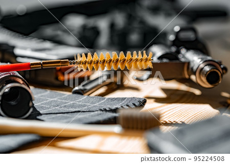 Black disassembled shotgun and cleaning tools on wooden table . Black disassembled shotgun and cleaning tools on wooden table . 95224508