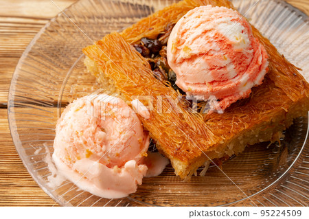 Turkish dessert kunefe served with ice cream on wooden background Turkish dessert kunefe served with ice cream on wooden background 95224509