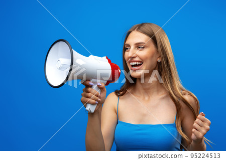Young pretty woman with a megaphone against blue background in studio Young pretty woman with a megaphone against blue background in studio 95224513