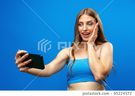 Confused young beautiful woman over blue background using mobile phone Confused young beautiful woman over blue background using mobile phone 95224572