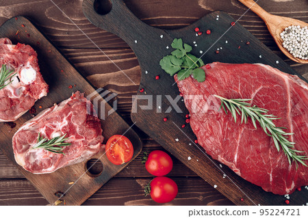 Raw beef steak with rosemary and spices on wooden board Raw beef steak with rosemary and spices on wooden board 95224721