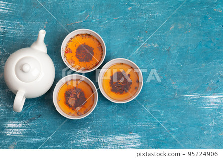 Tea concept. Different kinds of dry tea in ceramic bowls and cups of aromatic tea Tea concept. Different kinds of dry tea in ceramic bowls and cups of aromatic tea 95224906