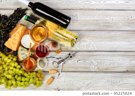 wine with branches of white grapes. On a wooden table. 95225024