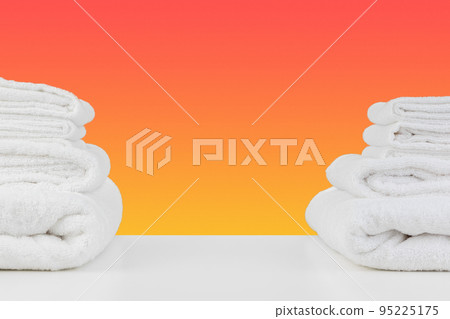 Stacked clean towels on white table against color background 95225175