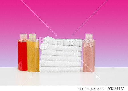 Pile of towels, bottles with shampoo on white table 95225181
