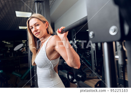 Middle-aged fitness woman doing squat exercise in a gym 95225183