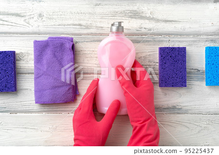 Hand in glove with cleaning supplies above white wooden background Hand in glove with cleaning supplies above white wooden background 95225437