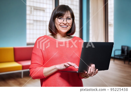 Middle aged female psychologist in office with laptop Middle aged female psychologist in office with laptop 95225438